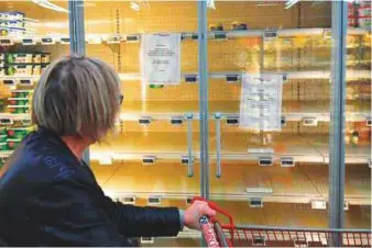  ?? AFP ?? A woman reads a sign that says, “Due to a shortage of the raw material to make butter, we are not able to supply and sell you this product” in a supermarke­t in Reze, France.