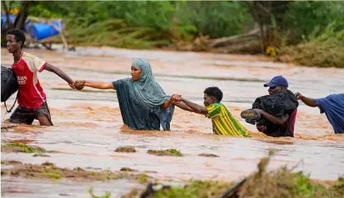  ?? ?? Residents cross a road damaged by El Niño rains in Tula, Tana River county in Kenya on 25 November 2023.