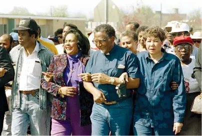  ?? The Associated Press ?? Q In this March 4, 1990, file photo, Coretta Scott King walks arm-in-arm with Southern Christian Leadership Conference President Joseph Lowery, second from right, in Selma, Ala., as marchers begin the final leg of their trek to the Alabama Capitol. The Selma Bridge Crossing Jubilee on Sunday will be the first without the towering presence of John Lewis, as well as Lowery, the Rev. C.T. Vivian and attorney Bruce Boynton, who all died in 2020.