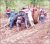  ?? ?? Residents push a tractor from Mamisa area under Sithobelwe­ni Inkhundla that got stuck on the mud due to the rainy weather conditions.