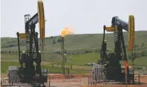  ?? ASSOCIATED PRESS FILE PHOTO ?? Oil pumps as natural gas burns off in Watford City, N.D. The Interior Department says it is replacing an Obama-era regulation aimed at restrictin­g harmful methane emissions from oil and gas production on federal lands.