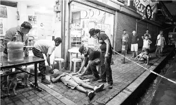  ??  ?? Police officers work at a crime scene, where an alleged drug dealer was killed during a police anti-drug operation, in Manila. — AFP photo