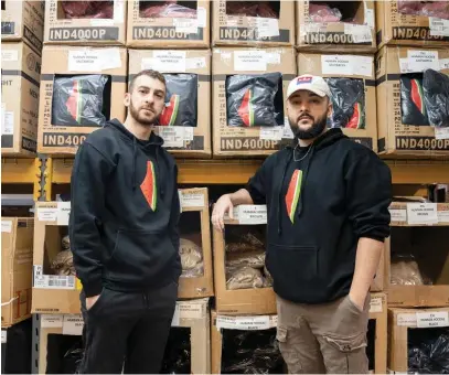  ?? PAT NABONG/SUN-TIMES ?? Wear The Peace co-founders Mustafa Mabruk (left) and Murad Nofal stand next to shelves of merchandis­e while wearing their “Freedom Melon” hoodies at the company’s Northwest Side warehouse. Sales of the crewneck version of the hoodie rose after Violet Affleck was spotted wearing one in Beverly Hills roughly two weeks ago.