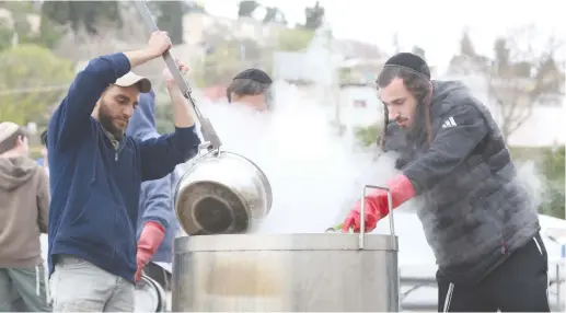  ?? (David Cohen/Flash90) ?? JEWISH FESTIVALS are part of the national calendar. Two men in Safed dip pots into hot water to rid them of hametz.