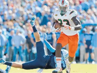  ?? GRANT HALVERSON/GETTY IMAGES ?? Miami’s Christophe­r Herndon IV breaks away from Cole Holcomb of the North Carolina Tar Heels for a touchdown in the second quarter of Saturday’s 12th straight win by the Hurricanes.