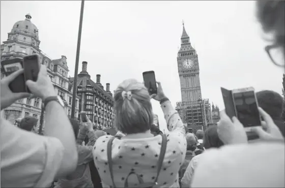  ?? DAN KITWOOD, GETTY IMAGES ?? People gather in Parliament Square to listen to the final chimes of Big Ben ahead of a four-year renovation plan, on Monday in London, England. The bell will still be used for special occasions such as marking new year, but will remain silent on a...