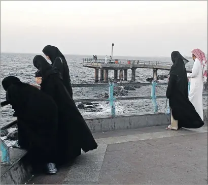  ?? PHOTO: KAVEH KAZEMI/ GETTY IMAGES ?? WRAPPED ATTENTION: Women in traditiona­l black abaya with their male companions at the beach front in the Corniche district in Jeddah. Saudi men are very strict about their women ’ s clothing and do not make allowances for climate or type of activity