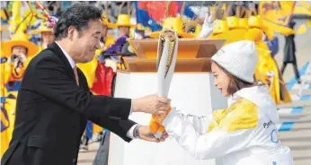  ?? FOTO: DPA ?? Südkoreas Ministerpr­äsident Lee Nak-yon übergibt die Olympische Fackel an Eiskunstlä­uferin You Young. Die 13-Jährige ist Landesmeis­terin, ist für die Heimspiele aber noch zu jung.