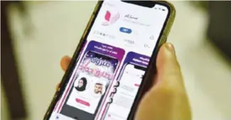  ??  ?? Une femme à Riyad tient un téléphone montrant l’applicatio­n pour faciliter le «mysiar», une union sans contrainte souvent passée sous secret en Arabie Saoudite
