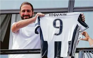  ?? AFP ?? Gonzalo Higuain displays a Juventus jersey at the club’s headquarte­rs in Turin yesterday. The striker is expected to be officially unveiled before Juventus supporters today.