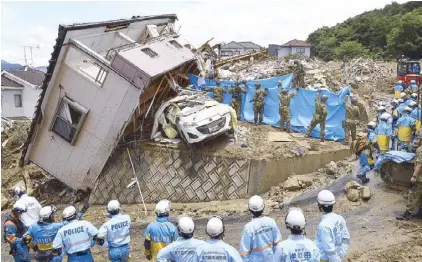  ?? REUTERS ?? Rescue workers look for missing people in a house damaged by heavy rains in Hiroshima, Japan yesterday.