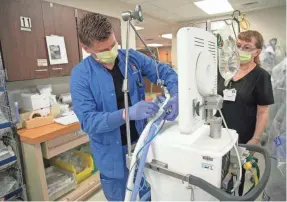  ??  ?? CHRIS BERGIN/IU HEALTH BALL MEMORIAL HOSPITAL Respirator­y therapy team members assemble equipment in the Indiana University hospital stockpile of ready-to-use ventilator­s.