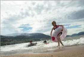  ?? The Canadian Press ?? Kids play in the waves of Skaha Lake as the Christie Mountain wildfire burns in the background in Penticton, Friday. See more fire photos on page B8.