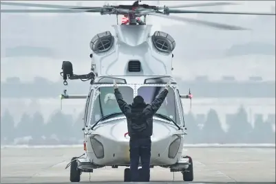  ?? XINHUA ?? A ground personnel clears an AC352 helicopter, designed by the Aviation Industry Corporatio­n of China, for take off.