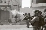  ?? Nasser Shivoukhi / Associated Press ?? Israeli police fire tear gas at Palestinia­ns during clashes in Bethlehem. Tensions have risen after police restricted Muslim access to a holy shrine.