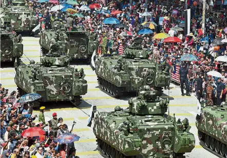  ??  ?? Steel of confidence: Malaysians watching armoured personnel carriers rolling past during the parade at the Kuantan Municipal Council field. — Bernama