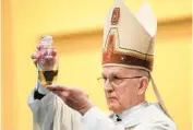  ?? KYLE TELECHAN/POST-TRIBUNE ?? Bishop Emeritus Dale Melczek holds a bottle of blessed oil during Maundy Thursday Mass at St. Mary of the Lake Church.