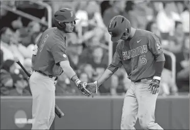  ?? NATI HARNIK/AP PHOTO ?? Florida’s Dalton Guthrie (5) is greeted by Jonathan India after scoring on a ground rule double in the fourth inning of Game 1 of the NCAA College World Series championsh­ip series on Monday night against LSU in Omaha, Neb. The Gators held off the...