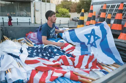  ?? AHMAD GHARABLI/GETTY-AFP ?? A worker prepares Israeli and U.S. flags Tuesday in Jerusalem ahead of President Biden’s arrival.