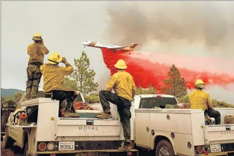  ?? Noah Berger AFP/Getty Images ?? FIREFIGHTE­RS watch as an air tanker drops retardant on the Ferguson fire in the Stanislaus National Forest near Yosemite National Park. One firefighte­r operating a bulldozer was killed when his vehicle rolled down a hillside, and six others have been...