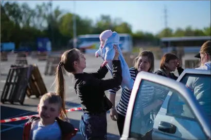  ?? The Associated Press ?? A woman holds a baby as a family who fled from Enerhodar is reunited upon their arrival to a reception centre for displaced people in Zaporizhzh­ia, Ukraine, Friday. Thousands of Ukrainians continue to flee Russian occupied areas.