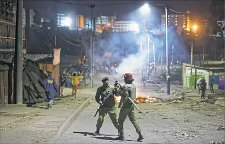  ?? Ben Curtis/Associated Press ?? A policeman reloads his tear gas grenade launcher after firing toward stone-throwing opposition protesters during clashes after the election results were announced Monday in the Mathare area of Nairobi, Kenya.