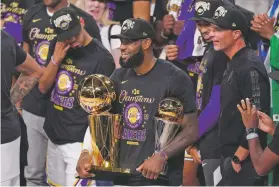  ??  ?? James holds the trophies as he celebrates with his teammates after the Lakers defeated the Miami Heat 106-93 in Game 6 of the NBA Finals on Oct. 11 in Lake Buena Vista, Fla.