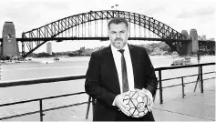  ??  ?? Ange Postecoglo­u holds a football as he poses for a photo in front of the Sydney Harbour Bridge. — AFP photo