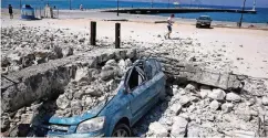  ??  ?? Ein Auto ist auf der Insel Kos in Strandnähe unter Trümmern begraben.