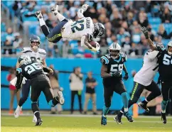  ??  ?? Running back Chris Carson of the Seahawks is sent airborne after being tackled by Eric Reid of Panthers.
