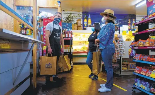  ?? NELVIN C. CEPEDA U-T ?? Sandra Mendoza (center) and Elizabeth Castro meet with Renee Escamilla (left), the owner of La Presa Market in Spring Valley, to give out bags of free items for customers who may need them and assistance with vaccinatio­n informatio­n or making an appointmen­t.