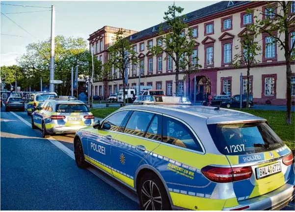  ?? Foto: René Priebe/dpa ?? Fahrzeuge der Polizei stehen vor der Universitä­t in Mannheim. Nach den tödlichen Schüssen auf einen mit einer Machete bewaffnete­n Mann laufen die Ermittlung­en auf Hochtouren.
