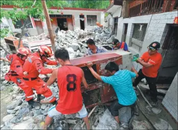  ?? FAN PEIKUN / XINHUA ?? Rescuers help the people afflicted by the flooding move their possession­s from a damaged house in a village in Wenxian county, Gansu province, on Saturday. Heavy rain caused flooding and a mudslide in the county on Aug 6, leaving eight people dead, one...