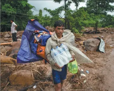  ?? JES AZNAR / GETTY IMAGES ?? Villagers wait to be evacuated near a damaged house and debris on Saturday in Attepeu, southeaste­rn Laos after a hydroelect­ric dam collapsed on Monday.