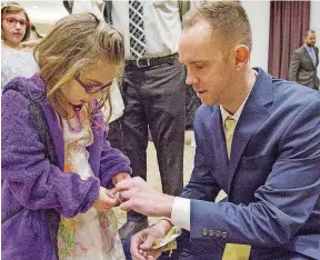  ??  ?? Matt Davis, 36, of Edmond, helps his daughter, Bree Davis, 5, put on a bracelet at the Daddy Daughter Dance.