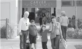  ?? NICK SWYTER Miami Herald ?? Parents pick up their children after school at George Washington Carver Elementary, located across the street from the Wawa site.