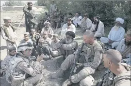  ?? DAVID GUTTENFELD­E — THE ASSOCIATED PRESS ?? Josh Habib, lower left, a 53-year-old translator for the U.S. Marines, speaks with Afghan villagers and two Marines in Afghanista­n in July. More than 200 Afghans landed Friday in the U.S. in the first of several planned evacuation flights for former translator­s and others.