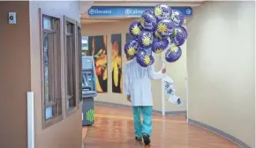  ?? ADAM CAIRNS/COLUMBUS DISPATCH ?? Aaron Raney, a resident surgeon at Ohiohealth Doctors Hospital in Columbus, carries a bunch of balloons back to his recovering patients. Last winter, his son got the idea to do a lemonade stand to help his dad‘s patients. George, 7, raised $124 in two afternoons in August.