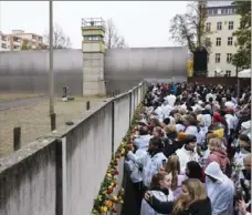  ?? Markus Schreiber/Associated Press ?? People stick flowers in remains of the Berlin Wall during a commemorat­ion ceremony Saturday in Berlin to celebrate the 30th anniversar­y of its fall.