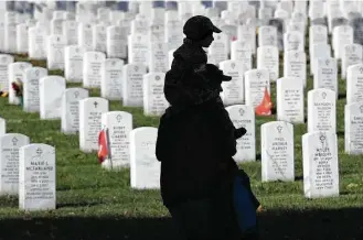  ?? Win McNamee / Getty Images ?? A young boy rides on his father’s shoulders while visiting Arlington National Cemetery on Veterans Day. The holiday pays tribute to those who served in the U.S. Armed Forces.