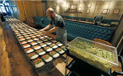  ?? CHARLES REX ARBOGAST/AP ?? ROOH executive chef Sujan Sarkar prepares part of the 450 meals that owner Manish Mallick will deliver via I Grow Chicago in Chicago’s Englewood neighborho­od.