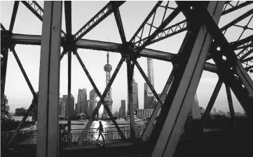  ??  ?? A man walks on a bridge in front of the financial district of Pudong in Shanghai, China. China will step up oversight in the banking sector this year to reduce financial risks, the country’s banking regulator said, stressing that long-term efforts...