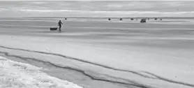  ?? PAUL A. SMITH / MILWAUKEE JOURNAL SENTINEL ?? A sturgeon spearer pulls a sled Saturday morning toward shacks on the ice along Lake Winnebago’s west shore.