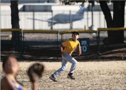  ?? PHOTOS BY JIM GENSHEIMER ?? With a parked plane in the background, Aiden Barragan, 9, positions himself in centerfiel­d to make a catch during practice at Eastridge Little League diamond on Monday in San Jose. Santa Clara County officials are planning to close the fields in a couple of weeks.