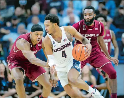  ?? STEPHEN DUNN/AP PHOTO ?? UConn’s Jalen Adams (4) controls the ball against Temple’s J.P. Moorman II (4) and Josh Brown (1) in a game on Feb. 28 at Storrs.
