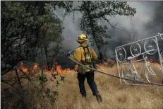  ?? MARCUS YAM/LOS ANGELES TIMES ?? A firefighte­r from Los Angeles helps stop the spread of a fire near homes in Redding on Sunday.