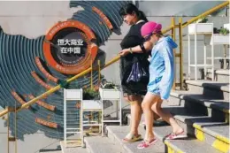  ?? AP PHOTO/ANDY WONG ?? A woman and a child walk by a map showing Evergrande developmen­t projects in China at an Evergrande city plaza in Beijing in late September.