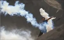  ?? KHALIL HAMRA, THE ASSOCIATED PRESS ?? A Palestinia­n protester throws back a tear-gas canister fired by Israeli soldiers during clashes on the Israeli border with Gaza on Friday.