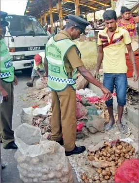  ??  ?? Sri Lanka’s Environmen­t Police is cracking down on food products unfit for consumptio­n being sold by traders at Gasworks Street in Pettah. Seen here is a policeman pouring kerosene oil on sacks of old potatoes. The bad stocks are then removed by the...