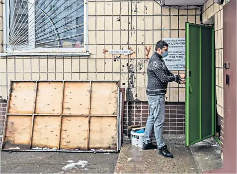  ?? ?? A civic official closes the outside door to a bomb shelter and, left, points to its location on a map of Kyiv